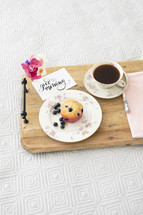 breakfast in bed, blueberry muffin, coffee, and flowers on a wooden tray 