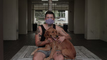 a man wearing a face mask petting his dog 