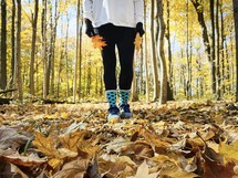legs of a woman standing in an autumn forest 