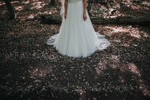 legs of a bride standing in the woods 