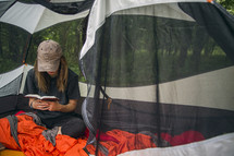 A woman sitting in a camping tent and reading the Bible.