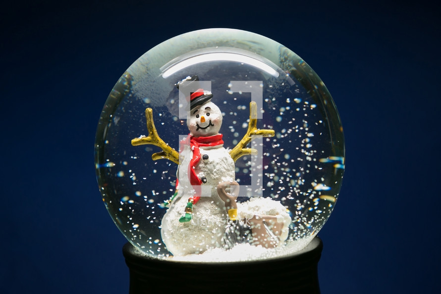 a snowman in a snow globe against a blue background 