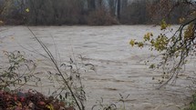 Large river flooding, rushing water flowing at high speed