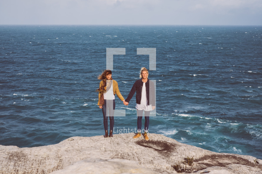 couple holding hands on a rocky beach 