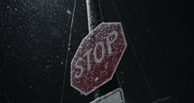 Slow motion snow at night falling on stop sign, Snowflakes falling in slow motion during winter snow storm at nighttime.
