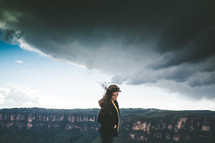 woman standing on a mountain top under a cloudy sky 