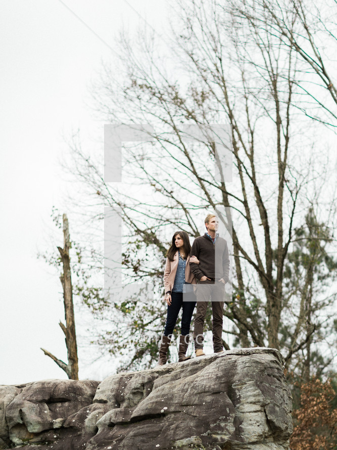 man and woman standing on the edge of a rock