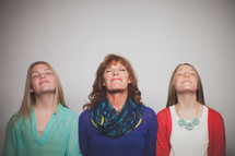 Mother and daughters lifting their heads in praise.