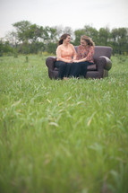 mother and daughter sitting on a couch talking together outdoors 