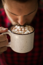 a man drinking a mug of hot chocolate 