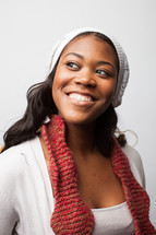 A smiling young woman wearing a hat and scarf. 