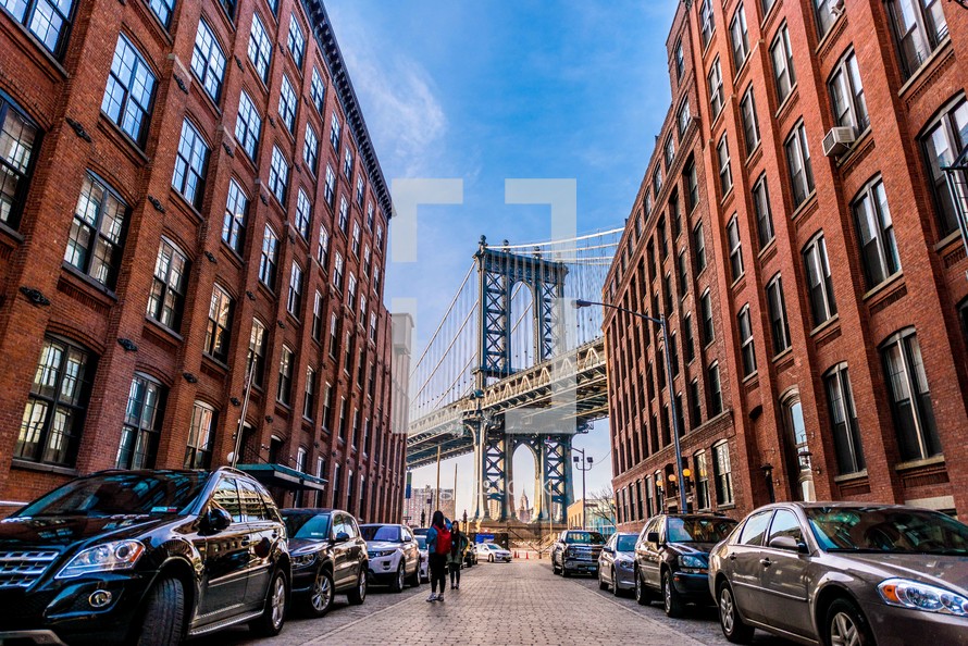 parked cars on a street and a view of the Brooklyn Bridge 