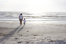 Mother and son walking on the beach.