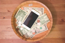 Iphone and money in a wood bowl 