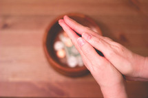 praying hands over a tithe bowl 