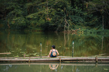 a girl sitting by a pond 