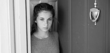 teen girl standing at a front door 