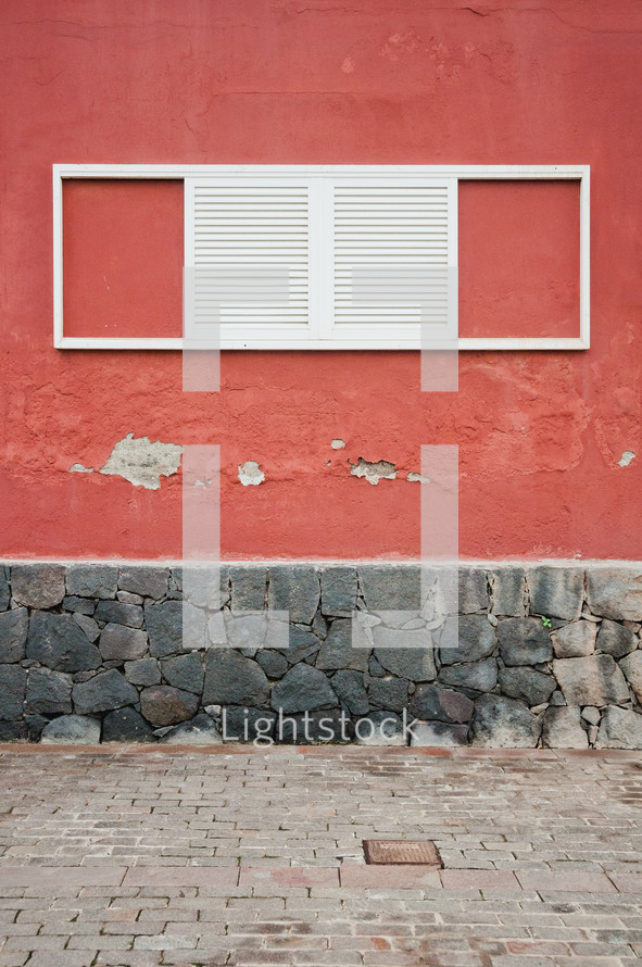 white shutters on a window on a red wall 
