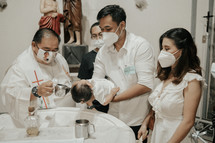 a priest baptizing an infant at a baptismal font 