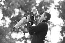 father holding a boy baby in the air