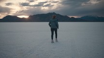 Young woman enjoying beautiful sunset and Mountain View in the Great Salt Flats
