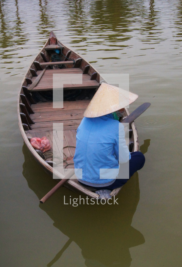 A Vietnamese lady sitting on a wooden boat