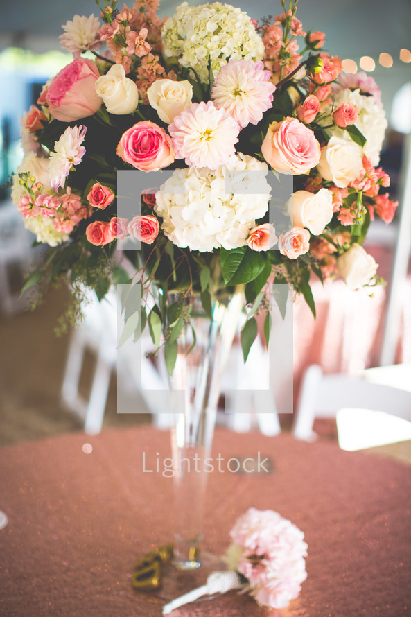 a centerpiece of flowers in a tall vase at a wedding reception 