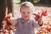 little girl playing in fall leaves 