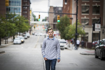 teen boy walking down the center of a city street 