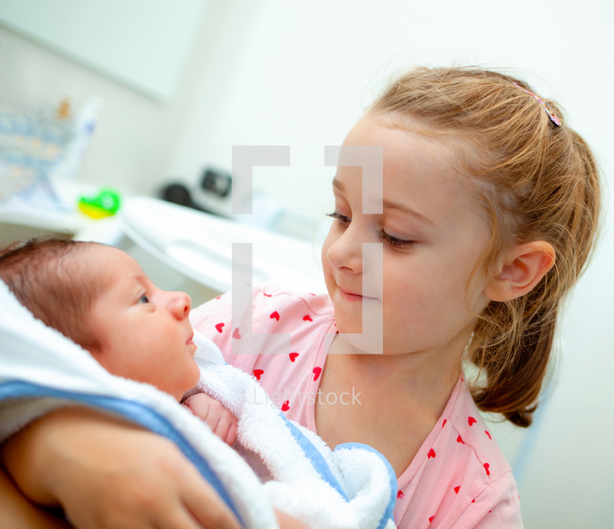 sister holding a newborn baby 