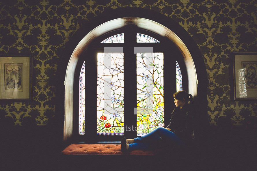 A woman sitting in a window thinking. 