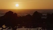Warm sunset behind rocks on coastline