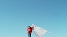a woman holding a white sheet blowing in the wind