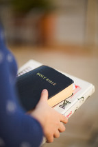 a woman carrying a Bible and journal 