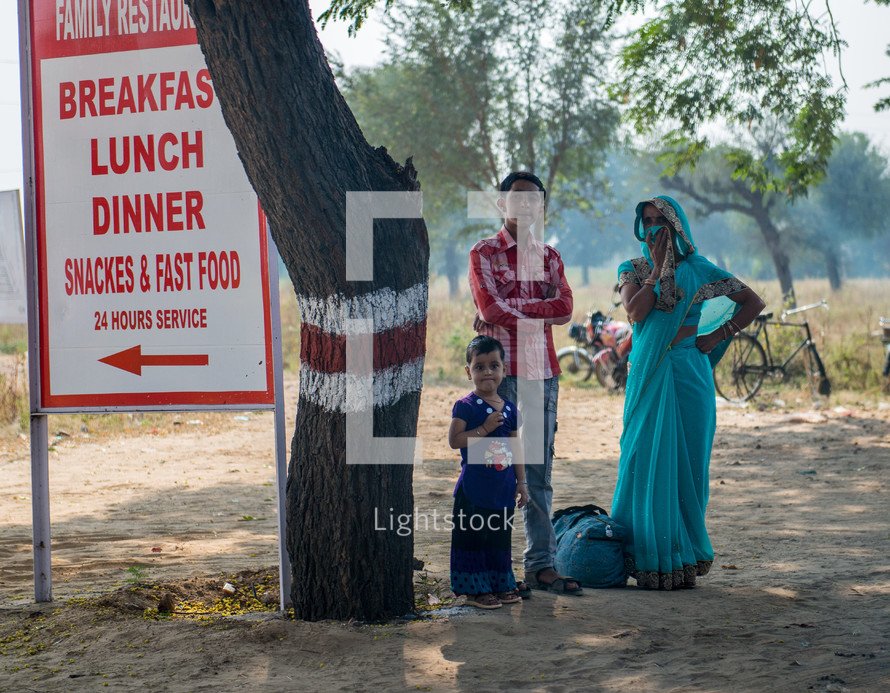 children in front of a restaurant sign in India 