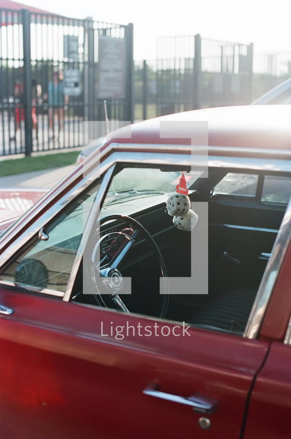 fuzzy dice hanging in a vintage red car 