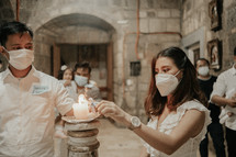 a mother and father lighting a candle at their infants baptism 
