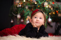 toddler girl on a fur rug under a Christmas tree