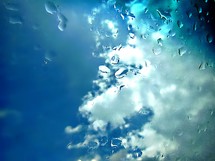 water drops on a camera lens and blue sky and white clouds 