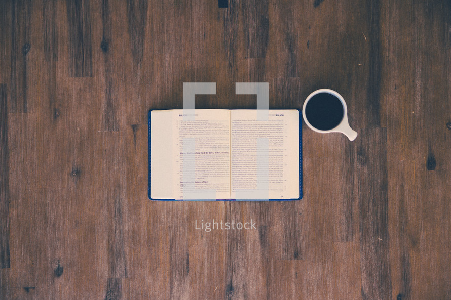 open Bible and coffee mug on a wood table 
