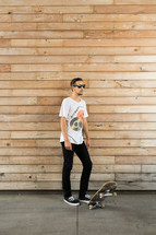 Man wearing sunglasses with a skateboard.