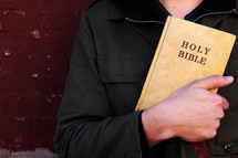 a man holding a Bible against his chest 