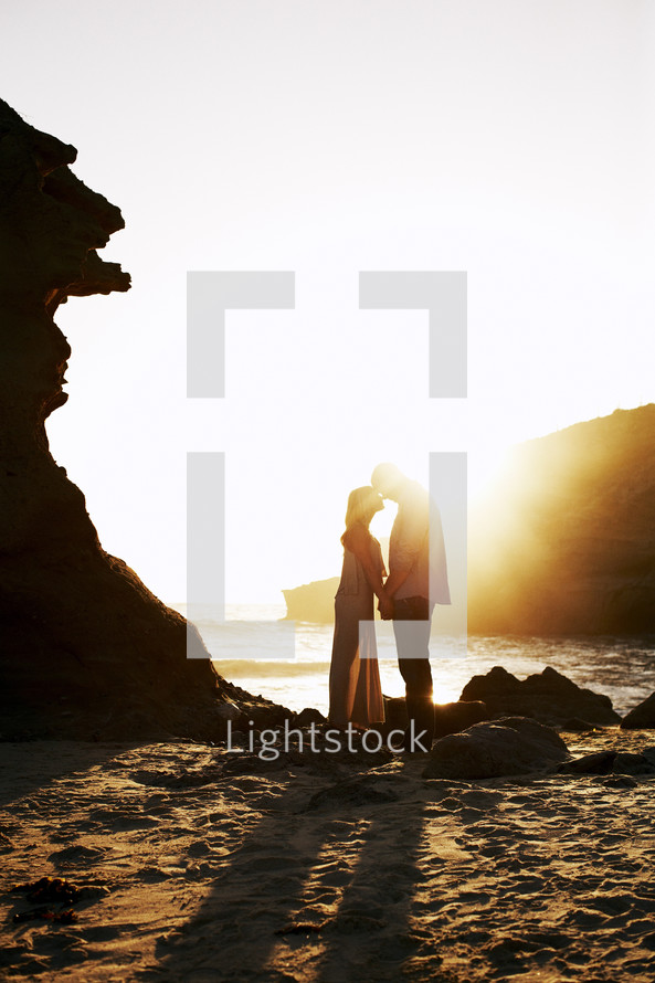 couple kissing under a sunburst on the beach