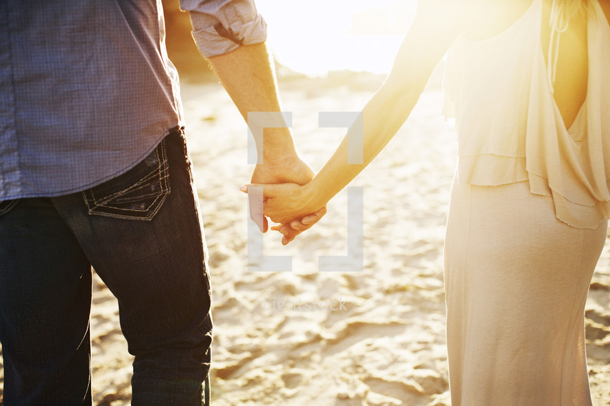couple holding hands walking on a beach