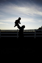 silhouette of a father holding up his son 