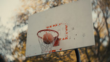 Close up of a basketball being shot on an outdoor basketball court on a sunny day