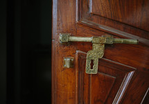a brass latch on a wooden door 
