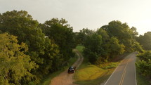 Drone Footage Aerial View of Car Driving down Gravel Road Between Trees. Rocky Road in Mississippi