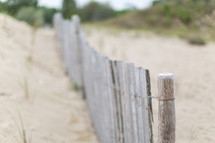 A wooden fence on a sandy beach.