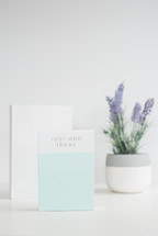 potted lavender plant, book, and journal on a white desk 